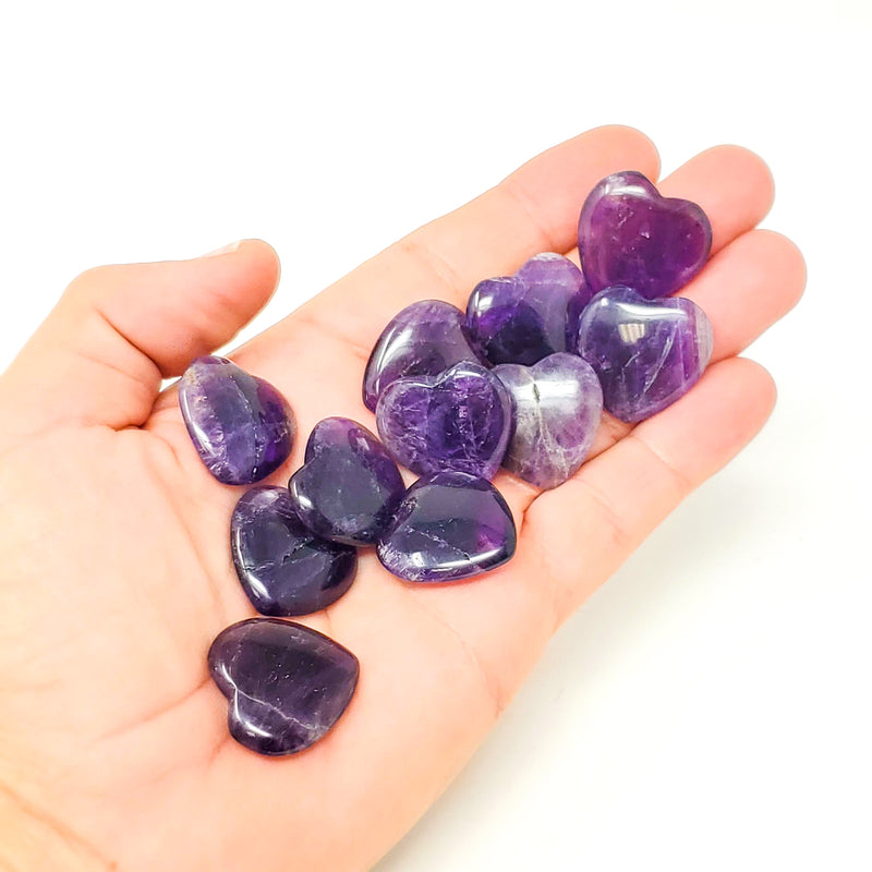 Variety of Amethyst Pocket Hearts held in a flattened, upward-faced hand on a white background