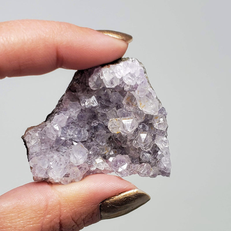 A hand holding up a Lavender Amethyst Cluster