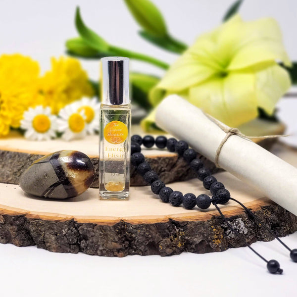 Contents of Keep On Keepin' On Morning Meditation Ritual Kit, including Lava Diffuser bracelet, Septarian Nodule Palm Stone, Energy Elixir anointing oil, and guided meditation scroll, all laid on stacked natural wood slabs with fresh flowers in the background 