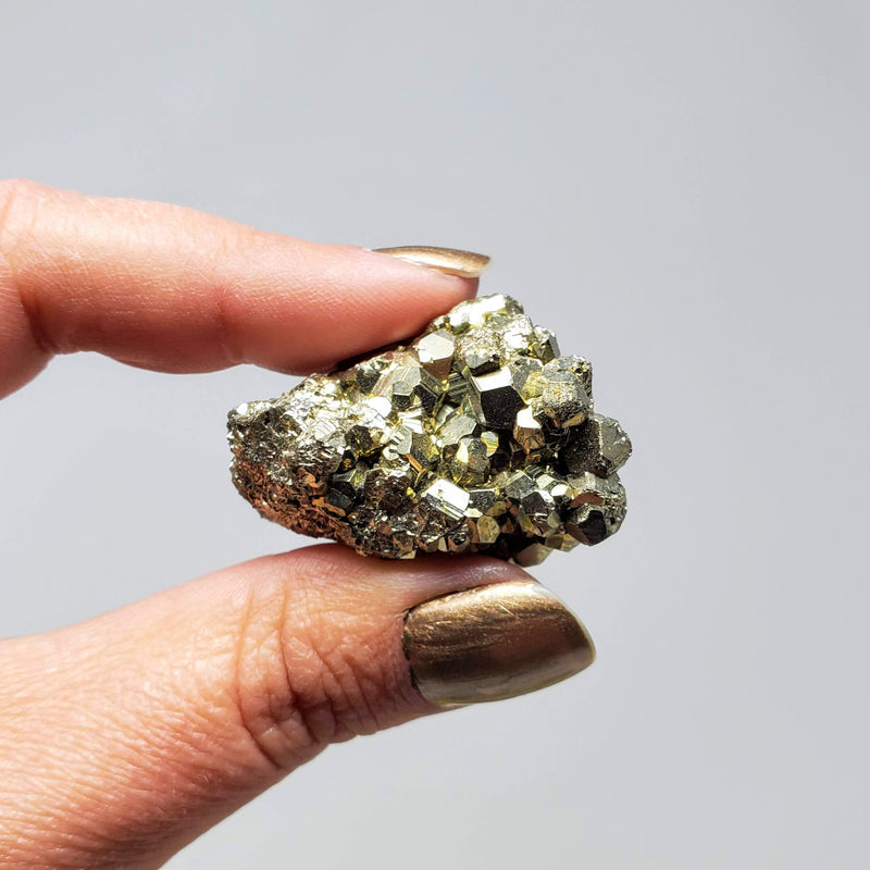 Pyrite Cluster held up between forefinger and thumb