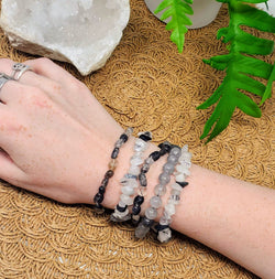 5 different styles of Black Tourmaline in Quartz bracelets adorn a wrist on a brown scalloped background