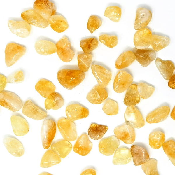 Citrine Tumbled Stones scattered about on a white background