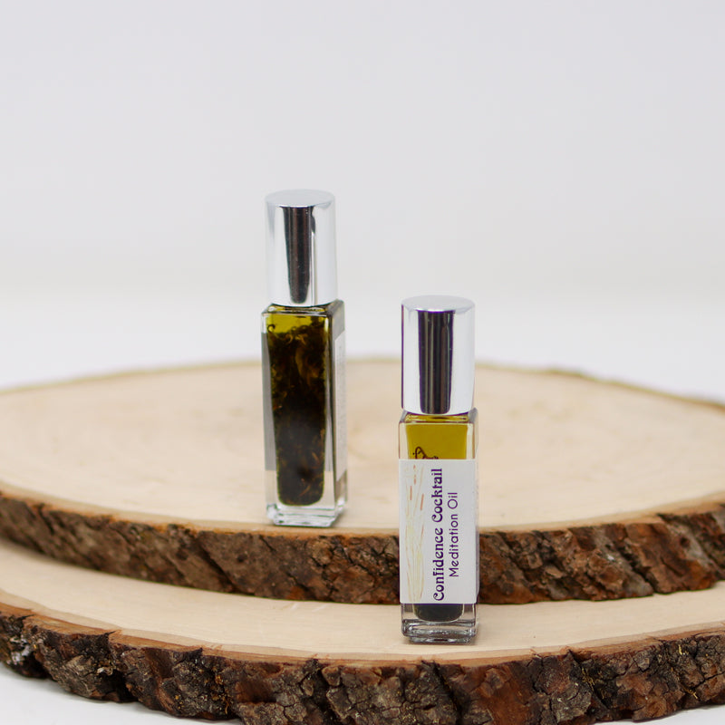 A front and back view of Confidence Cocktail Meditation Oil standing on natural wood slabs with a white background