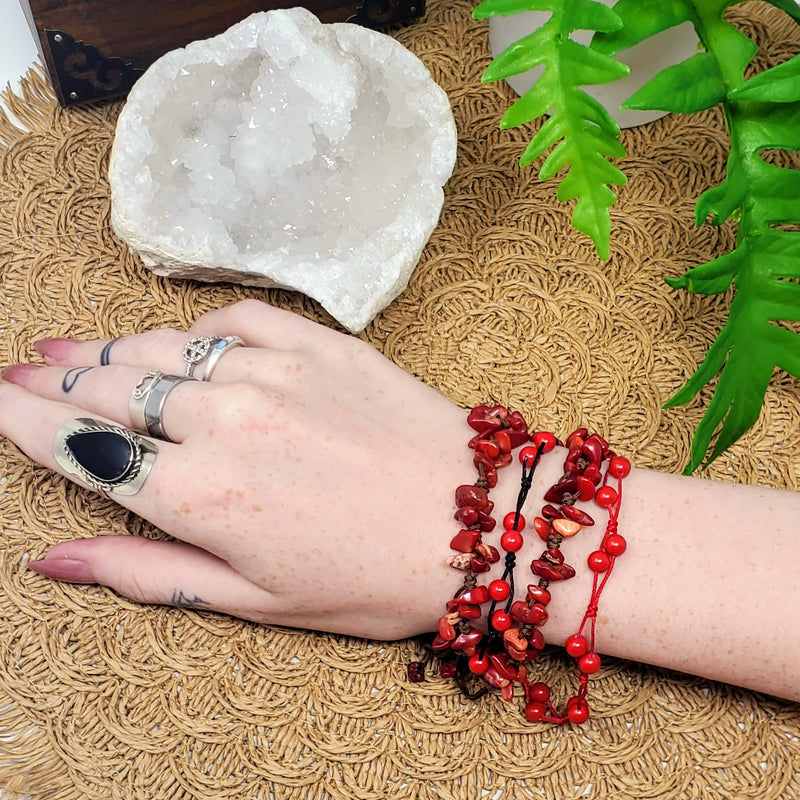 Different styles of Coral bracelets adorn a wrist next to a beautiful Apophyllite specimen, all on a brown scalloped background