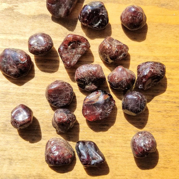 Garnet Tumbled Stones scattered about across a stained wood slab