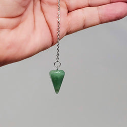 Green Aventurine pendulum draped over the palm of a hand on a gray background