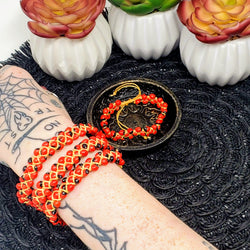 3 Huayruro Seed Bracelets on a tattooed arm, with potted succulents in the background