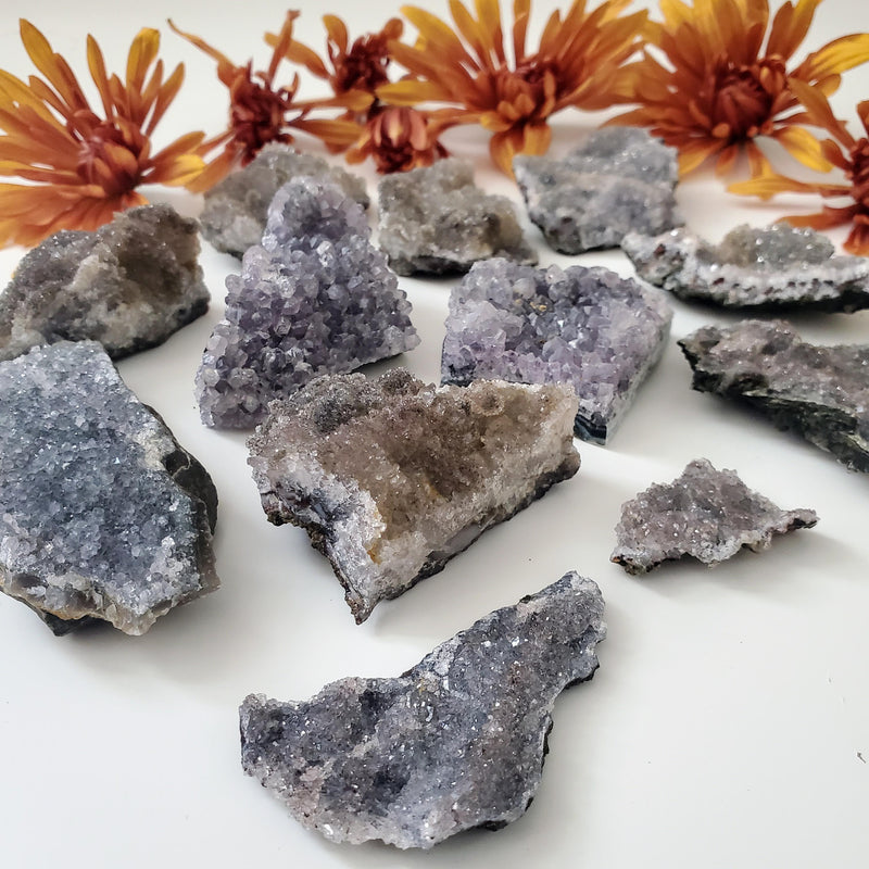 Lavender Amethyst Clusters displayed in front of fresh orange flowers on a white background