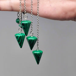 4 Malachite Pendulums draped over the side of a hand with a white background