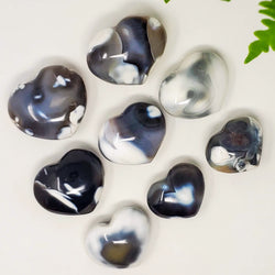 Orca Agate Heart Palmstones in a variety of sizes on a white background