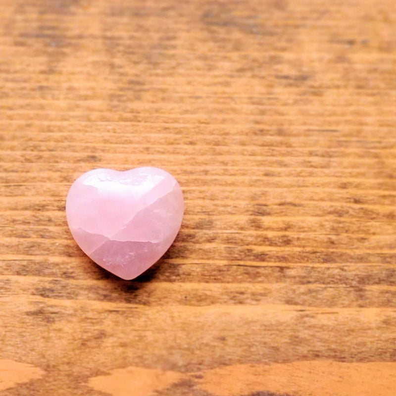 A single Rose Quartz Pocket Heart on a stained wood background