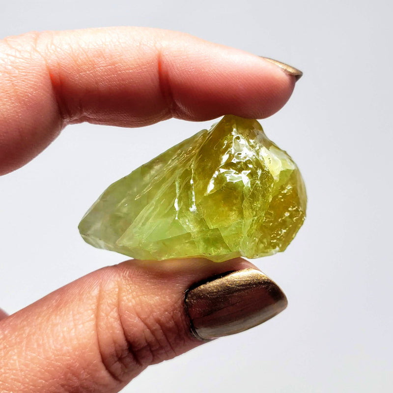A hand holding up a Raw Green Calcite Chunk