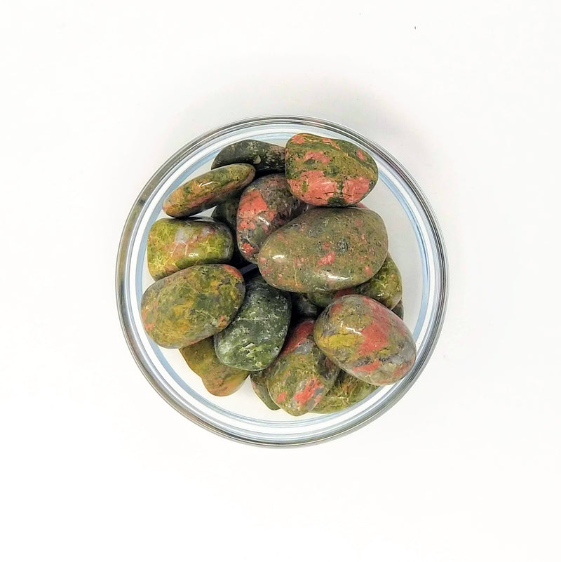 A clear bowl full of Unakite Jasper Tumbled Stones on a white background